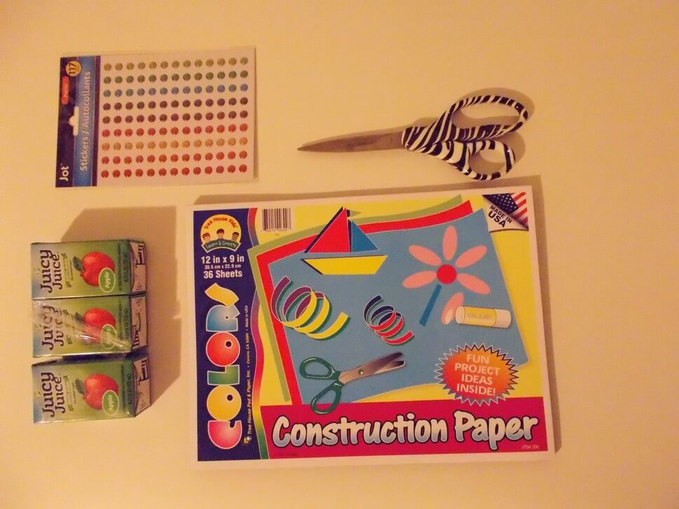 Tablet of construction paper, three Juicy Juice apple juice boxes, a collection of 3-D sticker spots, and zebra scissors