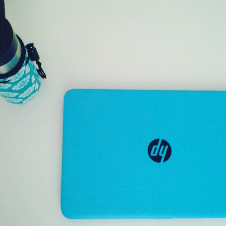 Overhead photo of stainless steel water bottle in turquoise-and-white hibiscus coozie, plus blue HP laptop