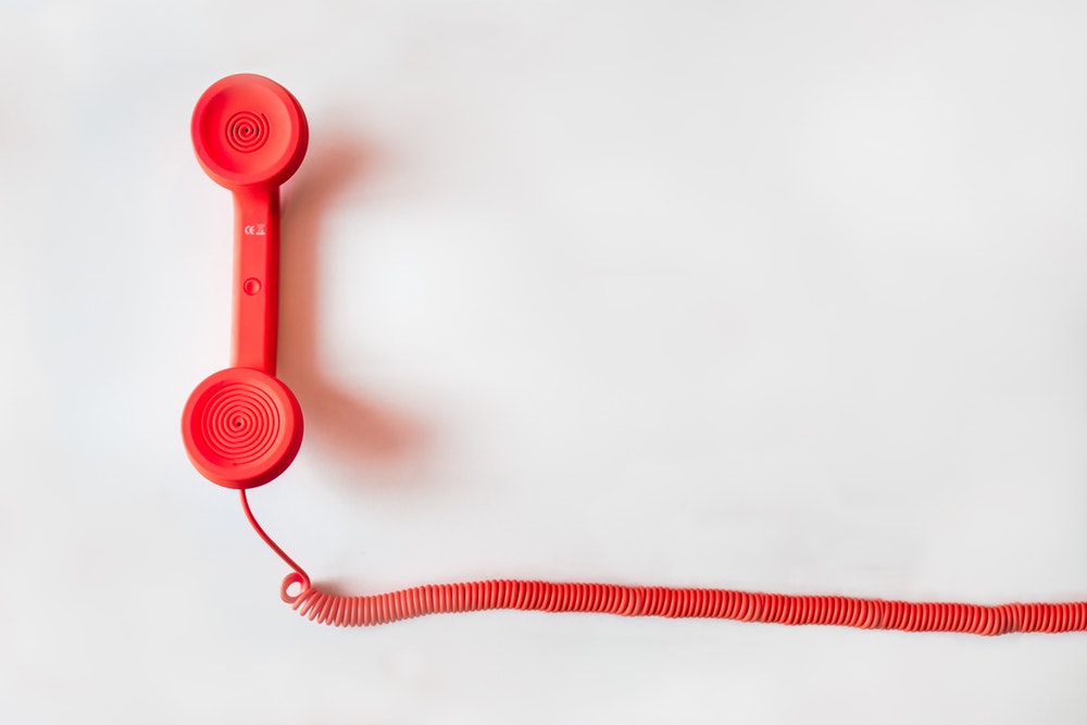 Photo of red corded phone on white background