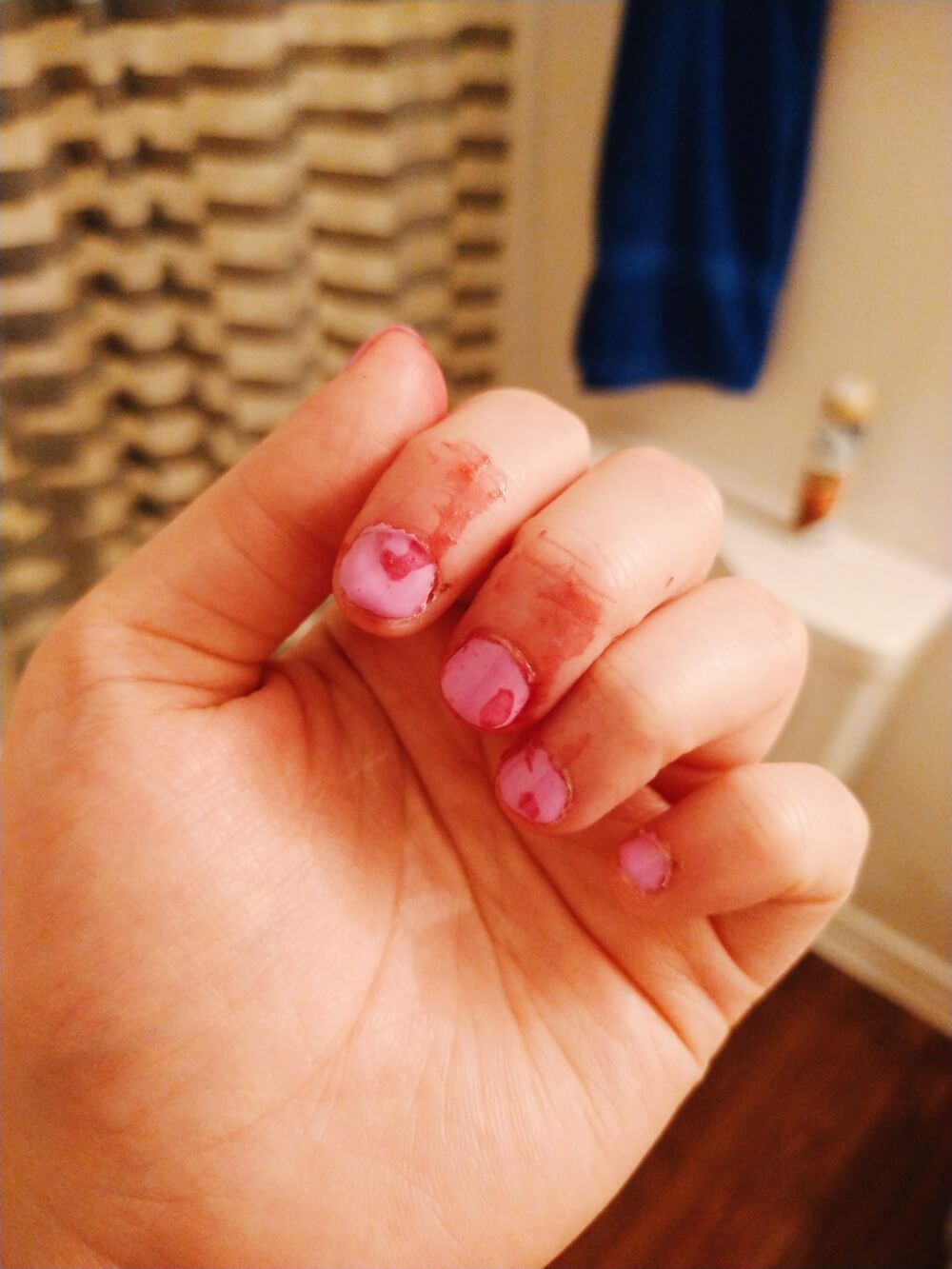 Blood orange on lavender nail-polished fingers on bathroom background to look like menstrual fluid