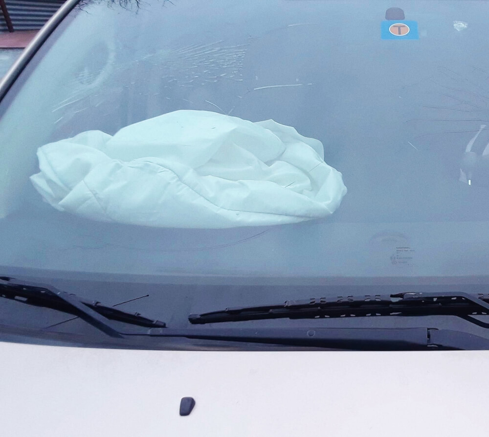 Cracked windshield, with deployed airbag sitting on dashboard