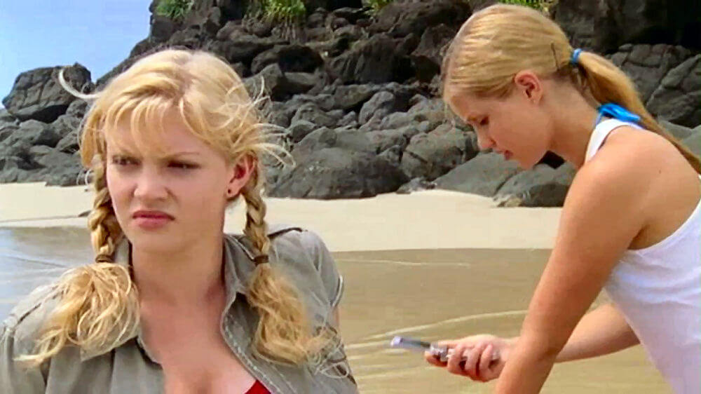 Emma looking at her phone while Rikki looks out to sea