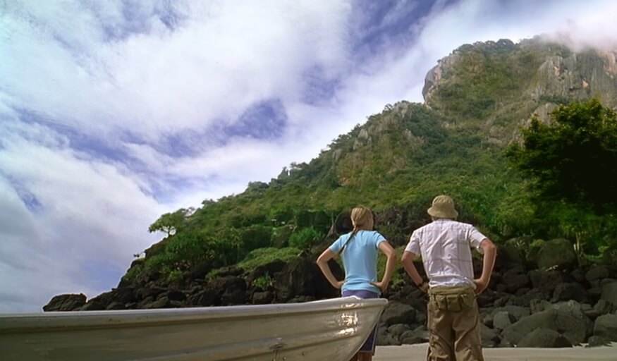 Emma and Lewis standing in front of his boat while looking towards the volcano on Mako Island