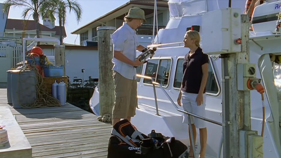 Lewis holds an underwater camera while standing on the dock next to Dr. Denman's boat, where she also stands