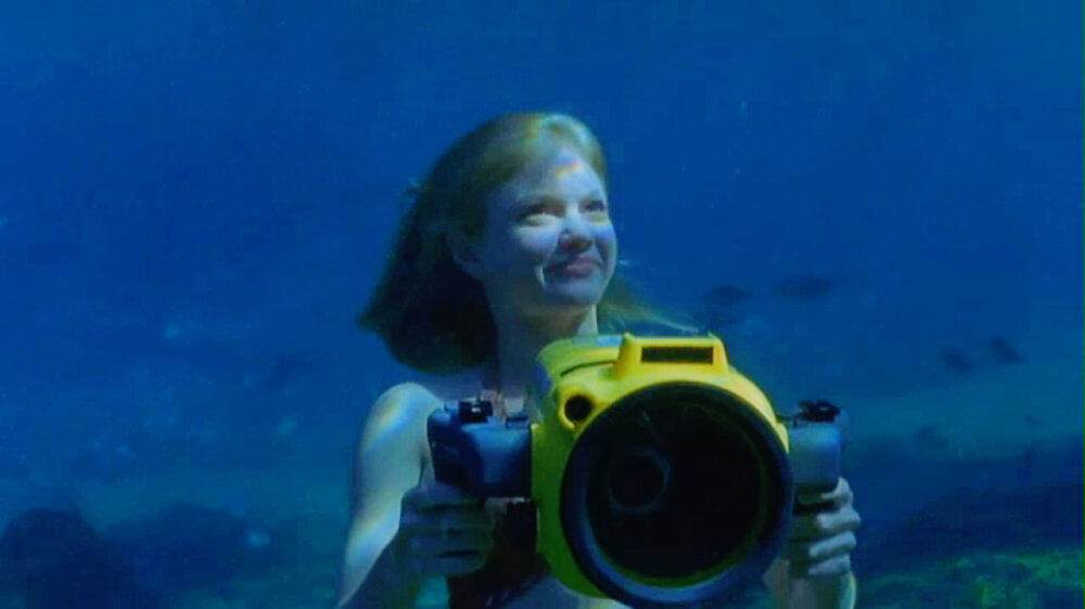 Rikki underwater in her mermaid form, with an underwater camera